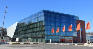 Stavanger Konserthus på en skyfri dag med vaiende oransje flagg, sett fra kaien.
